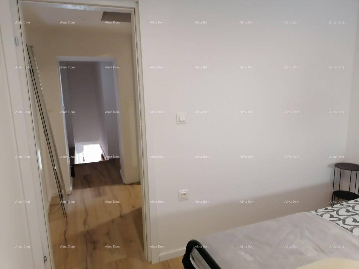 Schlafzimmer mit hellem Holzboden und Zugang zu einem weiteren Raum.