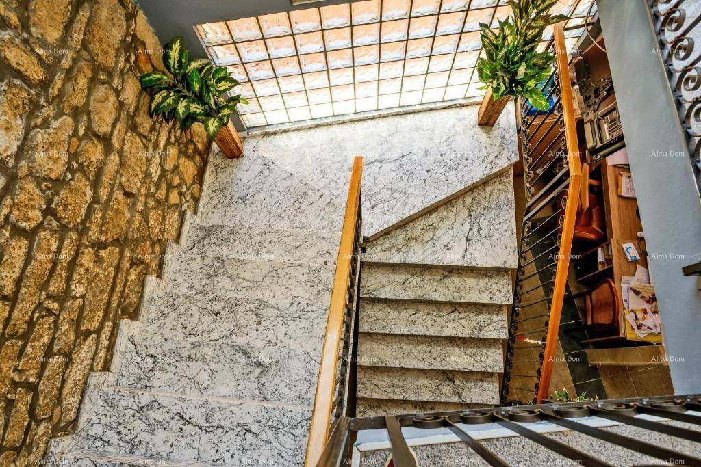 Marmortreppe mit schmiedeeisernem Geländer und Oberlicht, das natürliches Licht spendet.
