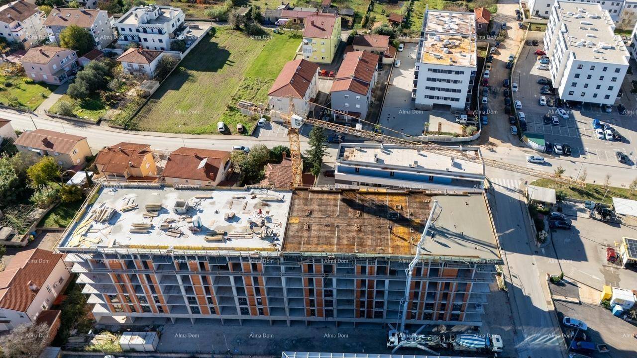 Vogelperspektive auf die Baustelle eines Gebäudes mit sichtbarer Dachkonstruktion und Kränen.