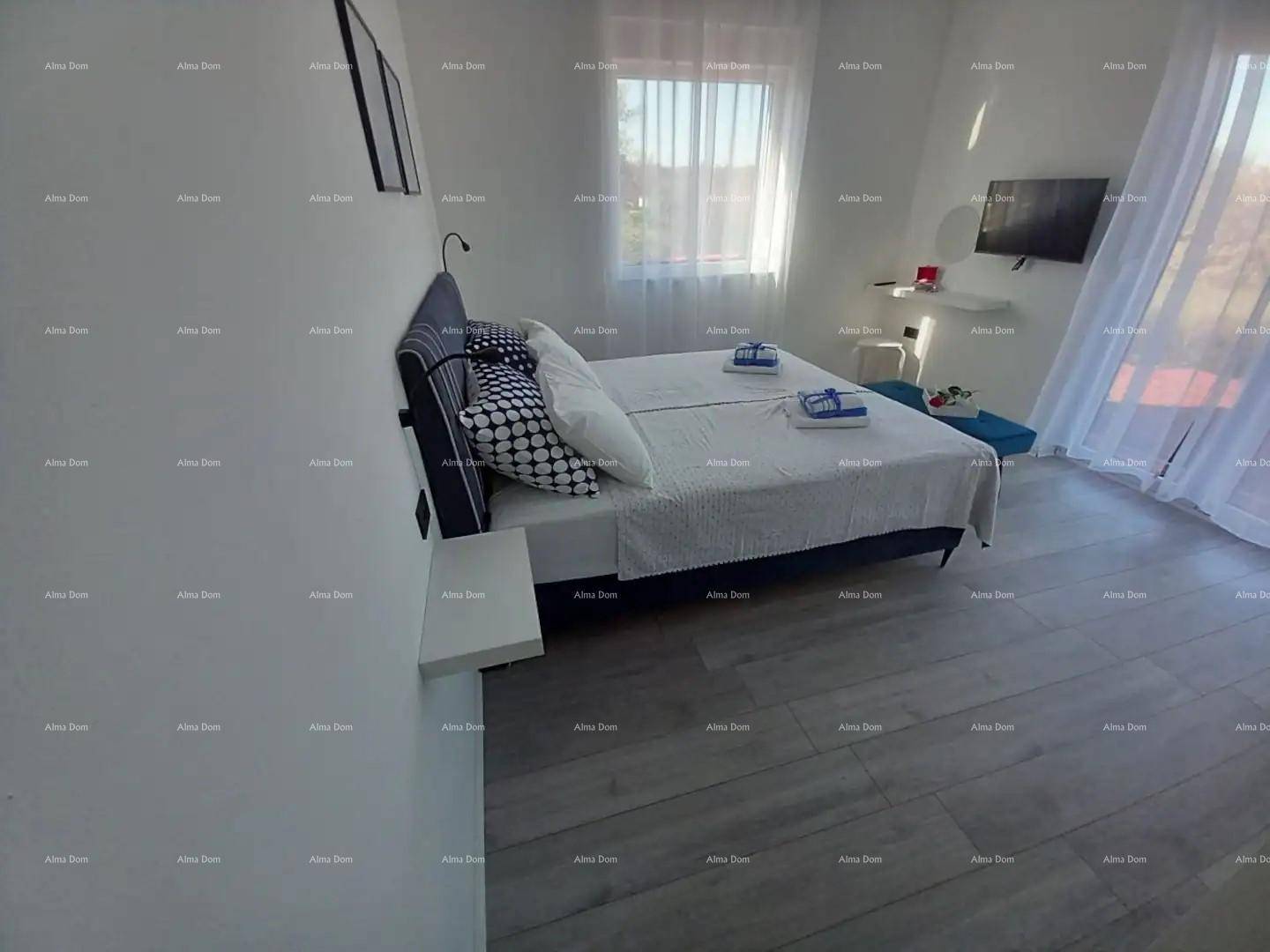 Helles Schlafzimmer mit Doppelbett, modernem Laminatboden und viel Tageslicht.