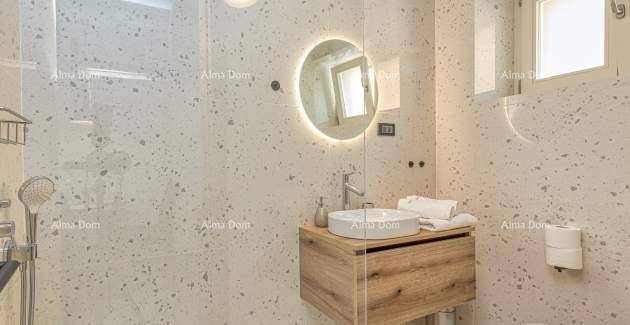 Helles Badezimmer mit modernem Waschtisch, beleuchtetem Spiegel und Fenster für Tageslicht.