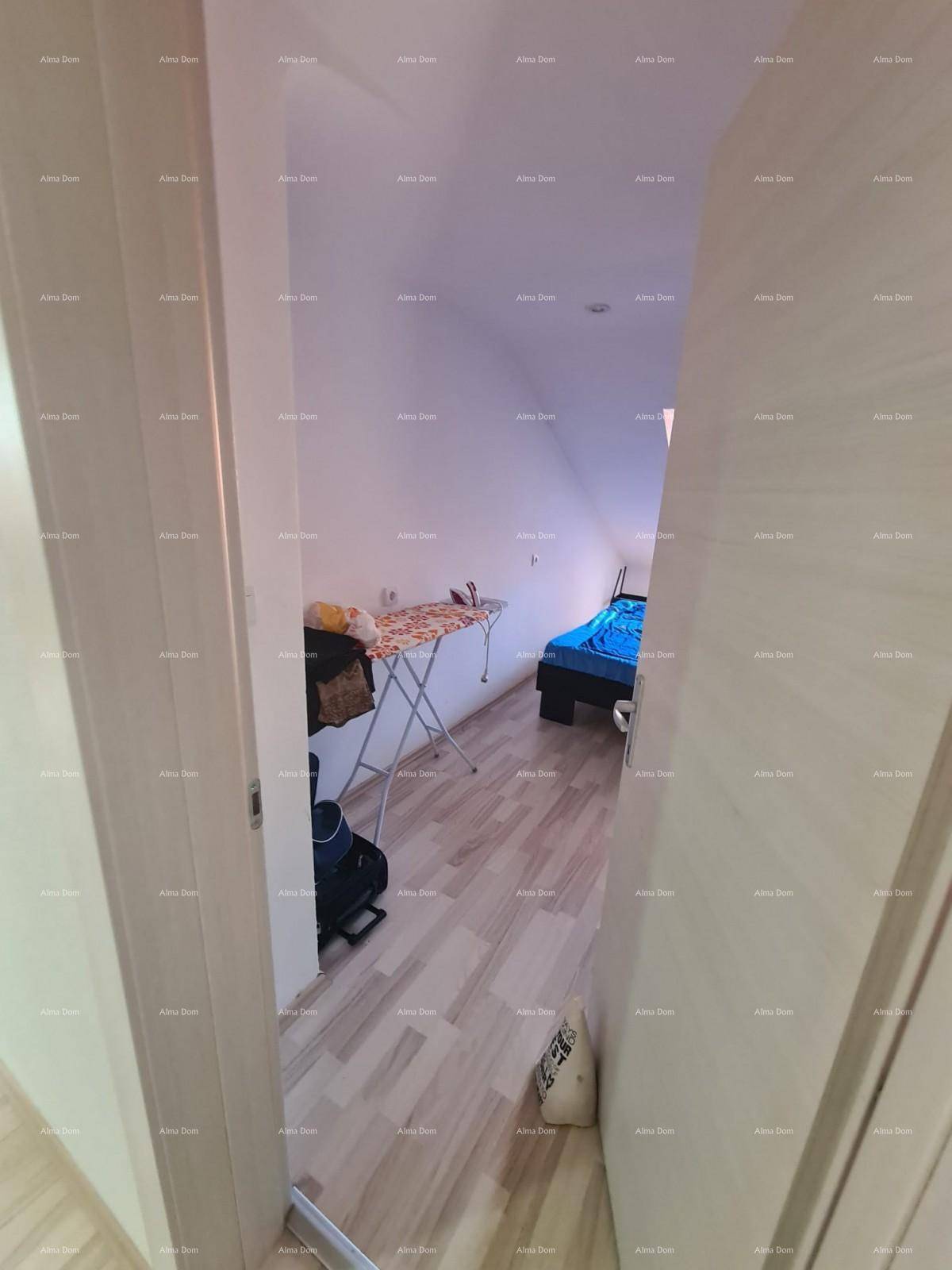 Blick durch eine Tür in ein Schlafzimmer im Dachgeschoss mit schrägen Wänden und einem Bett.