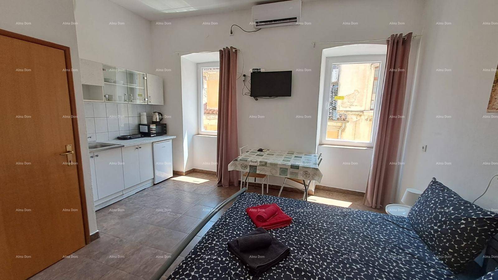 Helles Studio-Apartment mit Schlafbereich, Esstisch und integrierter weißer Küchenzeile, ausgestattet mit Klimaanlage.