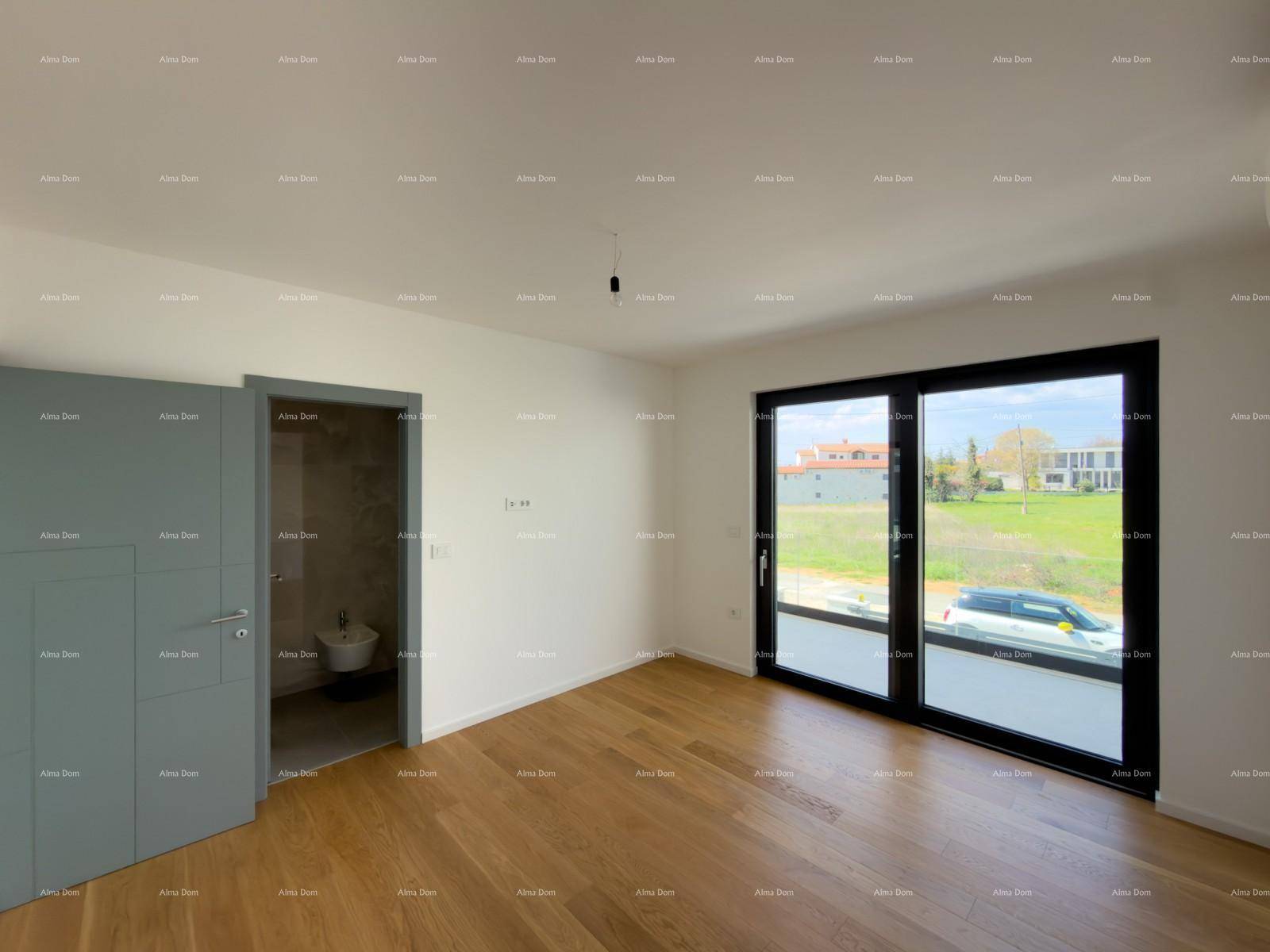Heller Raum mit Holzboden und großen Fenstern, daneben ein Zugang zu einem Badezimmer.