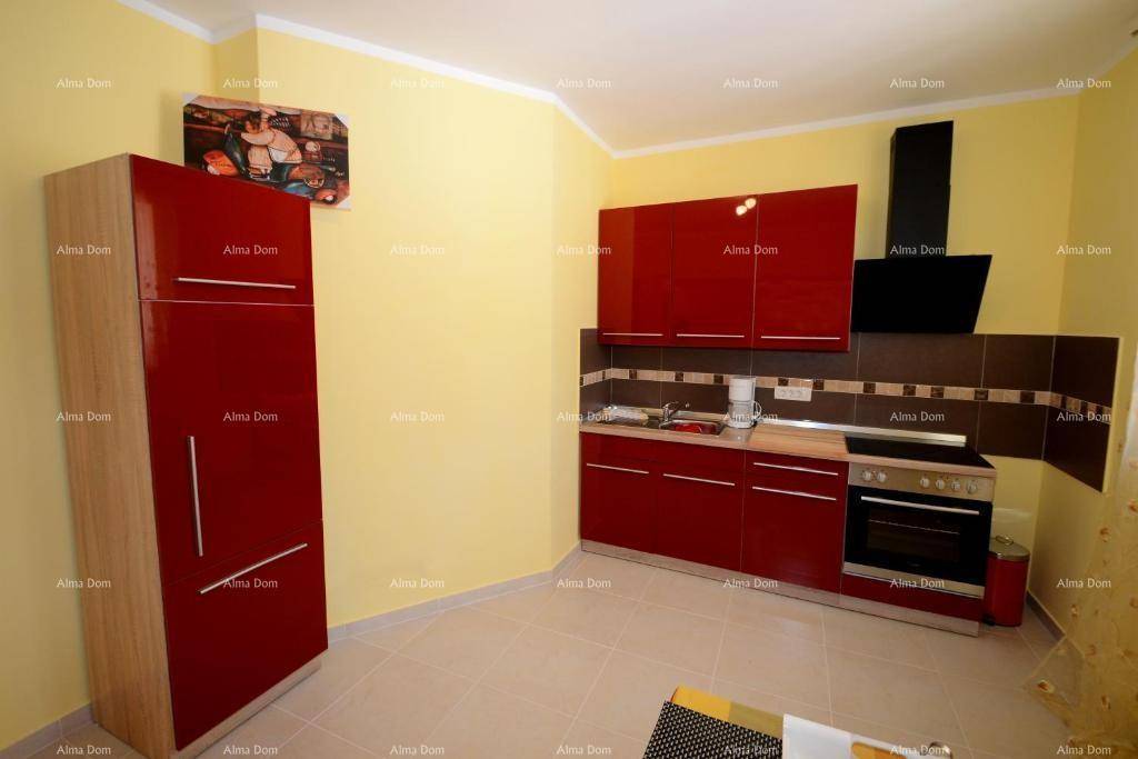 Moderne Küche mit roten Hochglanzschränken, Backofen und Dunstabzugshaube.