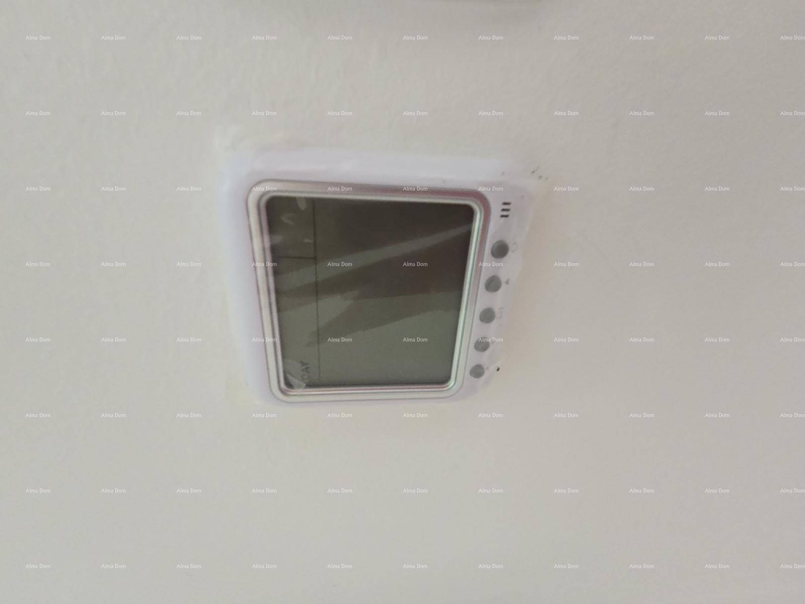 Detailaufnahme eines modernen Thermostats oder Bedienfelds an einer weißen Wand.