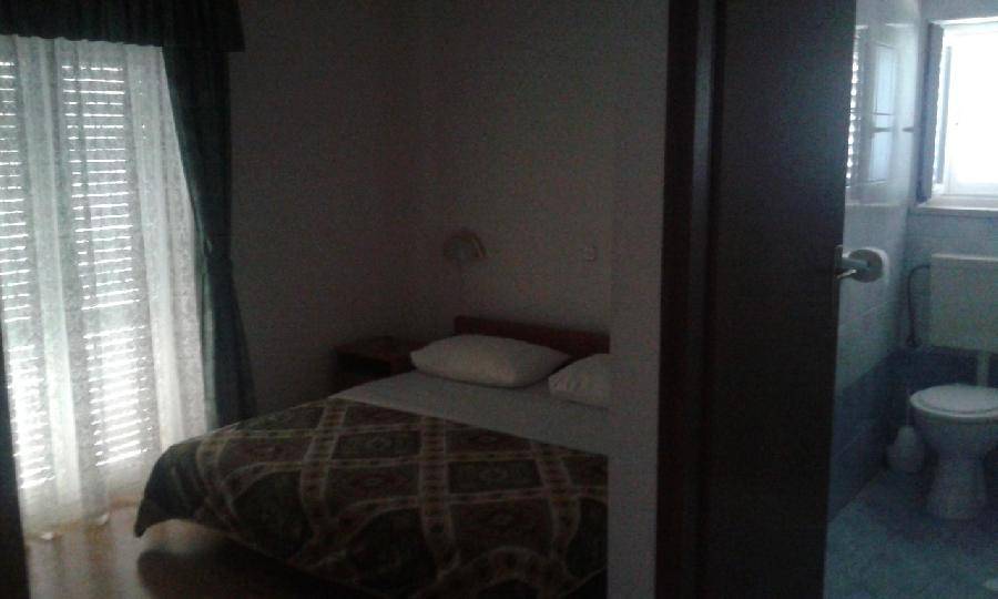 Schlafzimmer mit einem Bett und einem angrenzenden Badezimmer, das durch eine Tür sichtbar ist. 