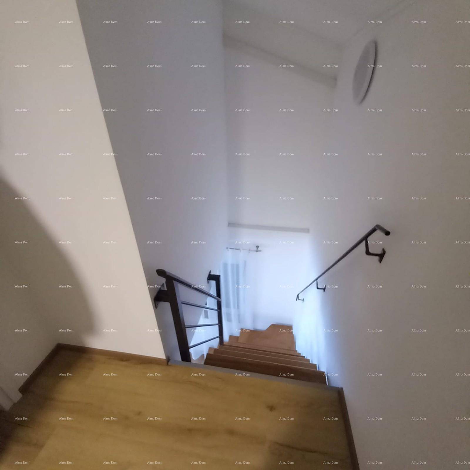 Treppenhaus mit Holzstufen und schwarzem Metallgeländer, das in den unteren Bereich führt.
