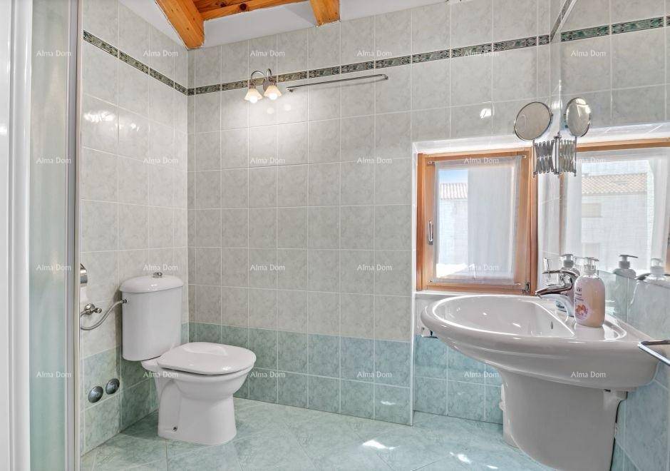 Helles Badezimmer mit Dusche, WC, Waschbecken und Fenster, in hellgrauen Fliesen gehalten.
