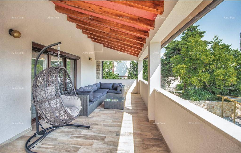 Geräumiger überdachter Balkon mit bequemen Lounge-Möbeln und Schaukelstuhl für Entspannung.
