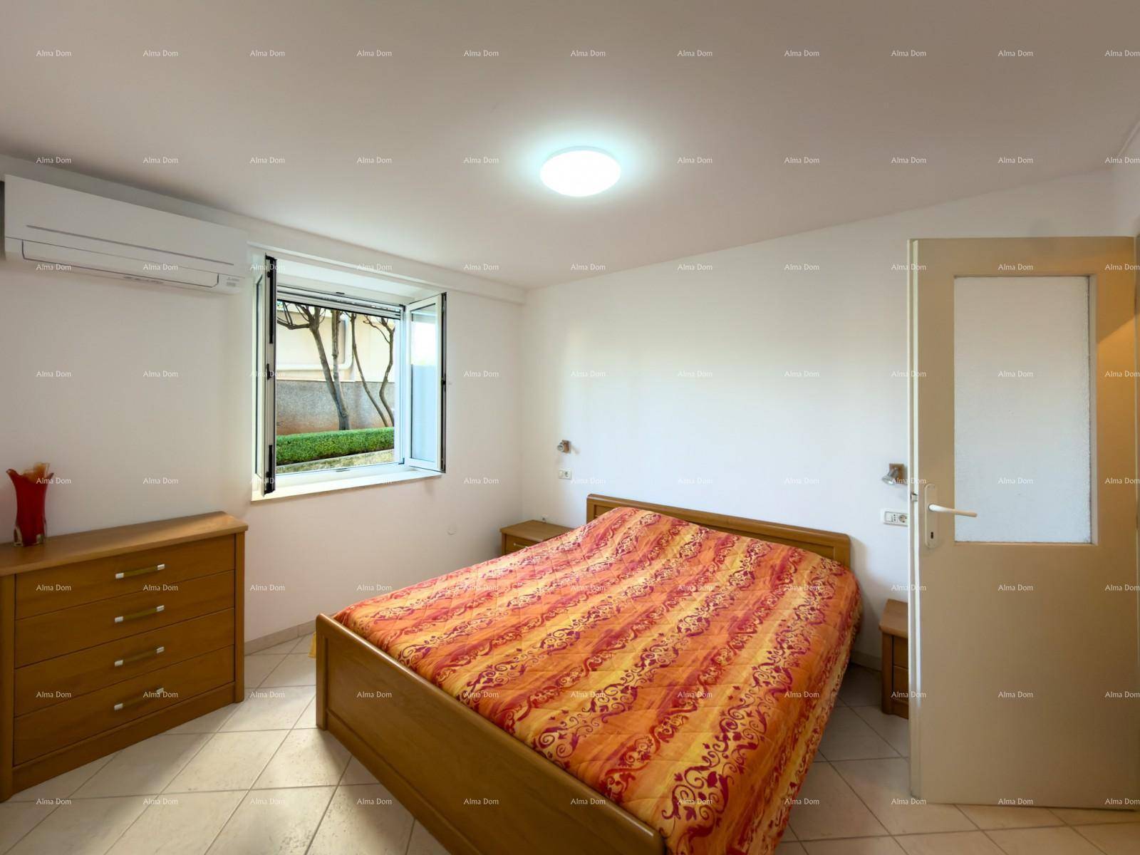 Schlafzimmer mit Doppelbett, Kommode und Fenster mit Blick auf den grünen Gartenbereich.