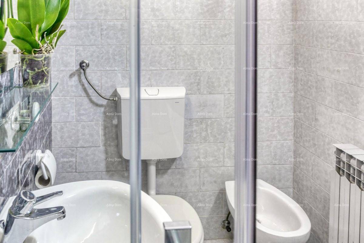 Badezimmer mit hellgrauen Fliesen, Toilette, Bidet und Heizkörper.