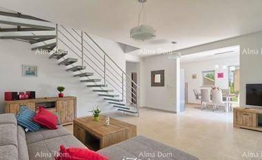 Geräumiges Wohnzimmer mit moderner Treppe, bequemer Couch und Blick auf den Essbereich.