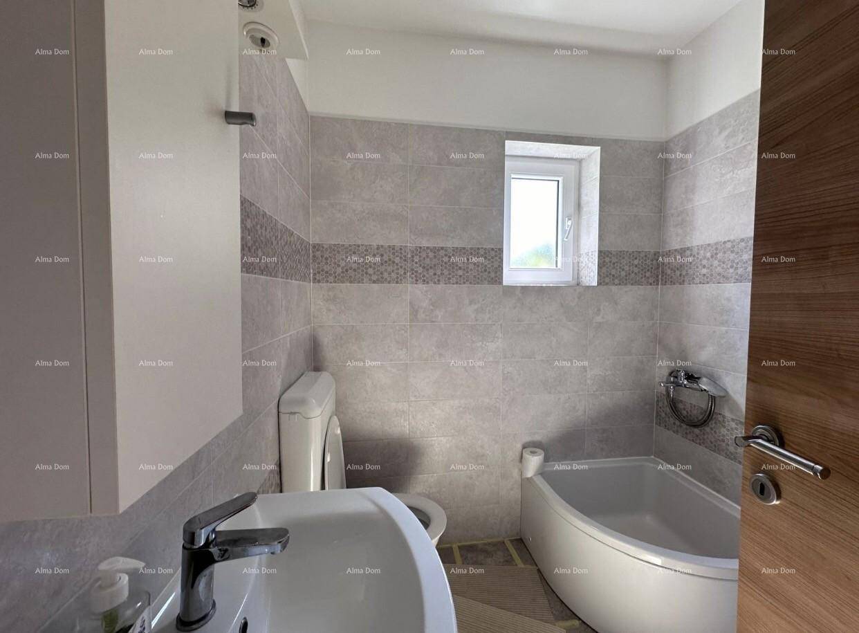 Badezimmer mit Waschbecken, Toilette und Badewanne, in hellen Grautönen gefliest.