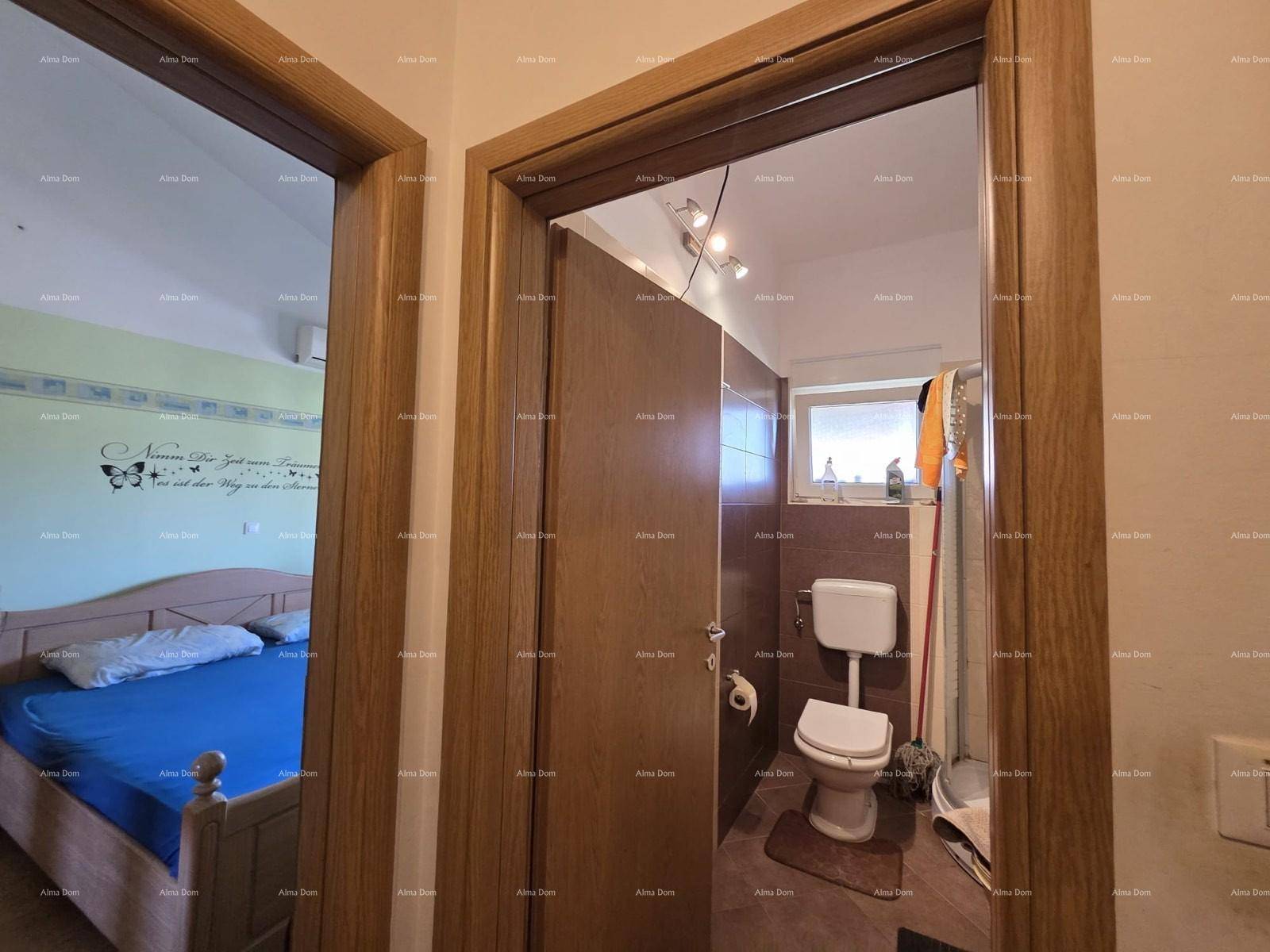 Kleines WC mit Toilette und Fenster, durch eine Holztür vom Flur aus zugänglich.