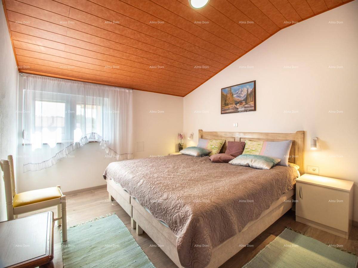 Helles Schlafzimmer mit Doppelbett, Dachschrägen und einem Fenster mit Blick ins Grüne.