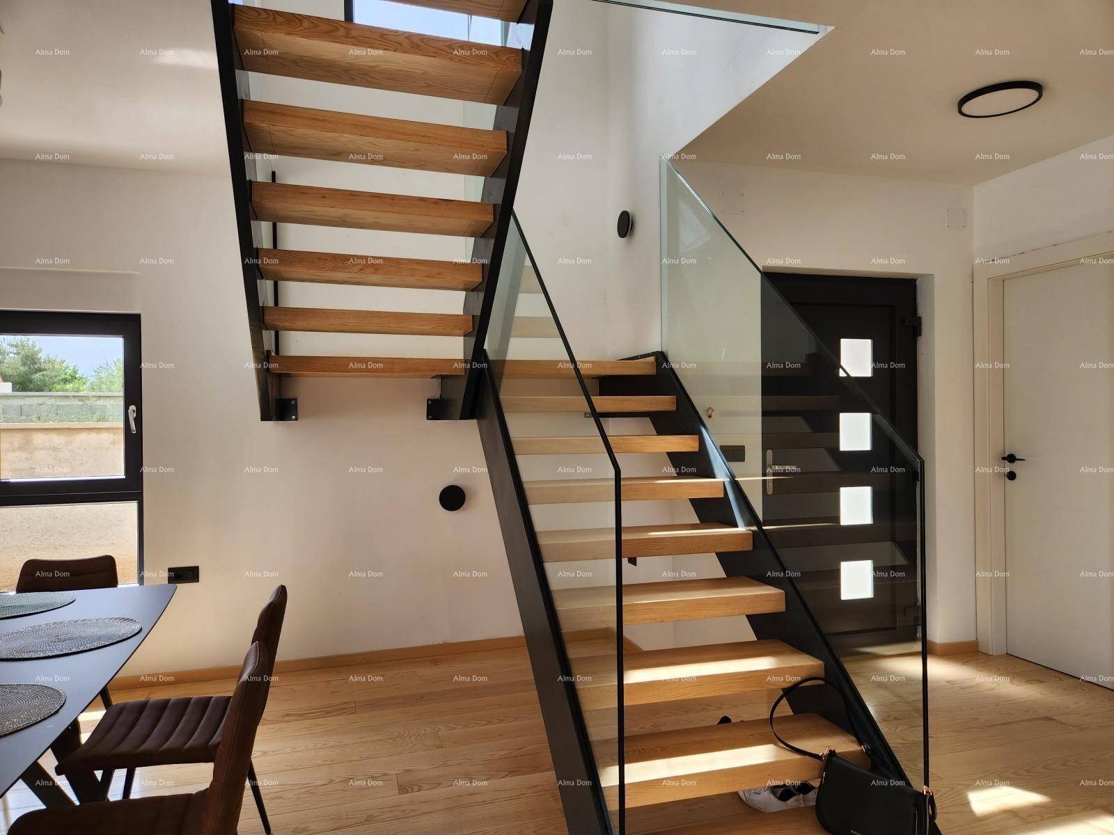 Moderner Essbereich mit Holzboden und einer eleganten Treppe mit Glasgeländer, die die Etagen verbindet.