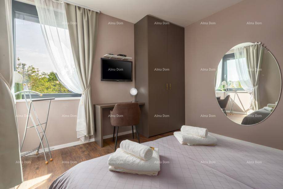 Helles Schlafzimmer mit Doppelbett, Schreibtisch und großem Fenster, das viel Tageslicht hereinlässt.