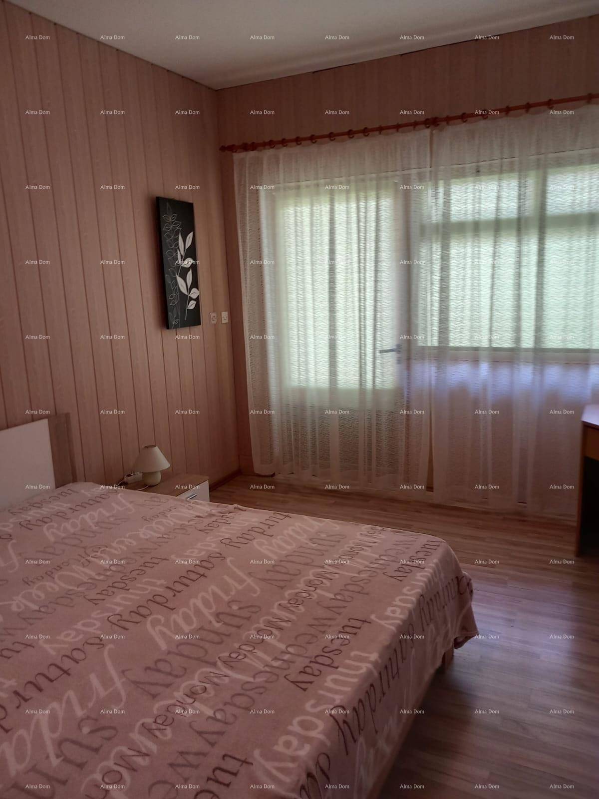 Schlafzimmer mit Doppelbett und großem Fenster, das viel Tageslicht hereinlässt.