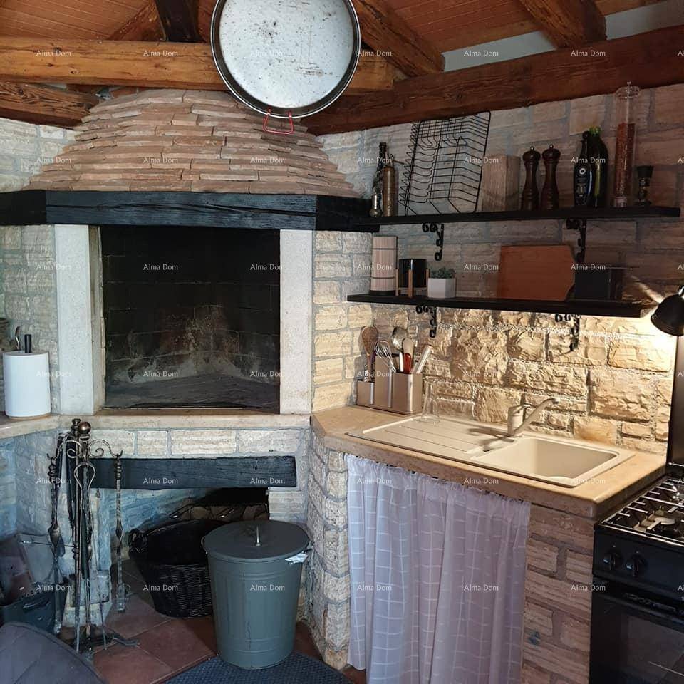 Rustikale Küche mit großem gemauertem Kaminofen, Steinwänden und sichtbaren Holzbalken an der Decke.