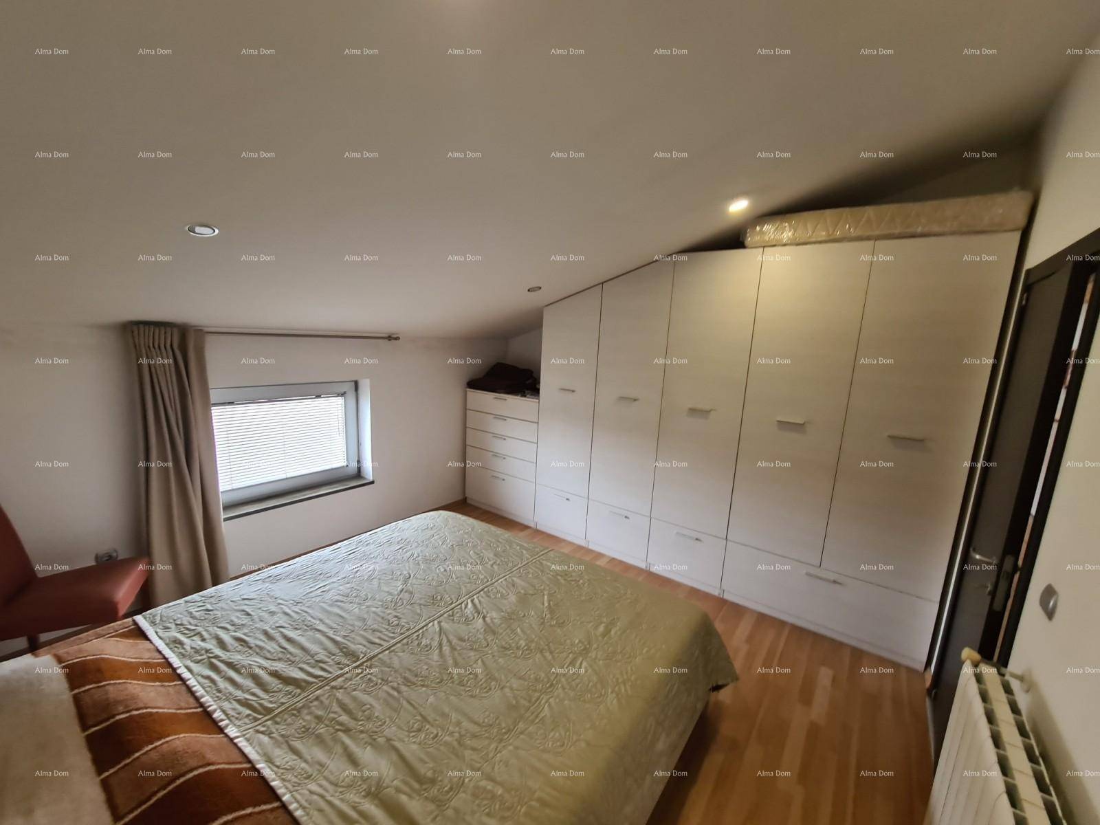 Schlafzimmer im Dachgeschoss mit Holzboden, Einbauschränken und einem kleinen Fenster.