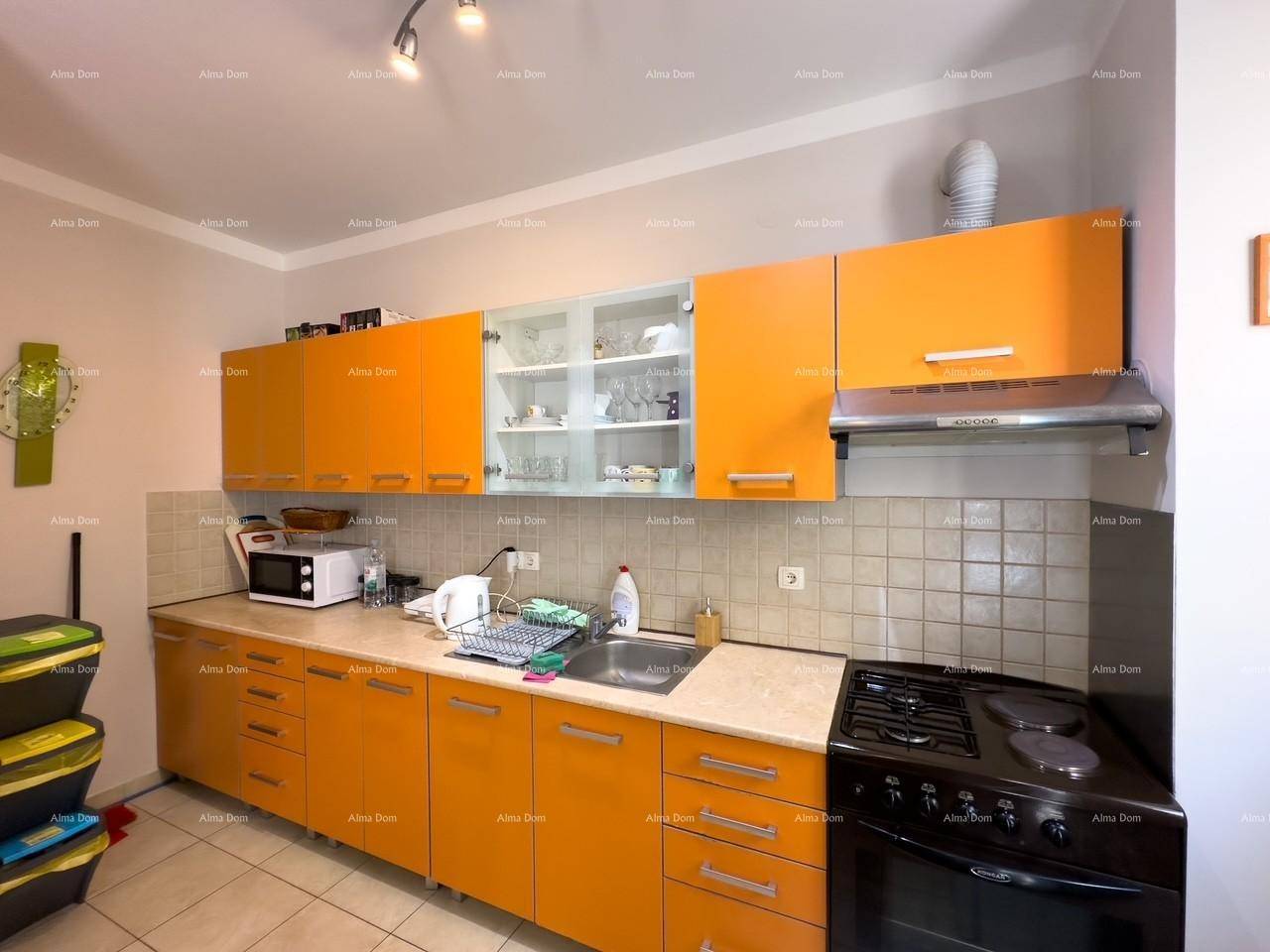 Detailansicht der Küche mit orangefarbenen Unterschränken, Spüle und Gasherd, praktisch eingerichtet.