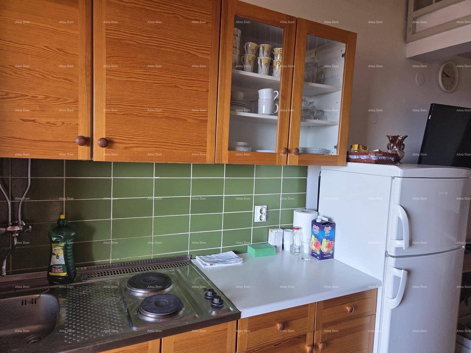 Detailansicht der Küchenzeile mit Spüle, Kochfeld, Kühlschrank und Holzschränken.
