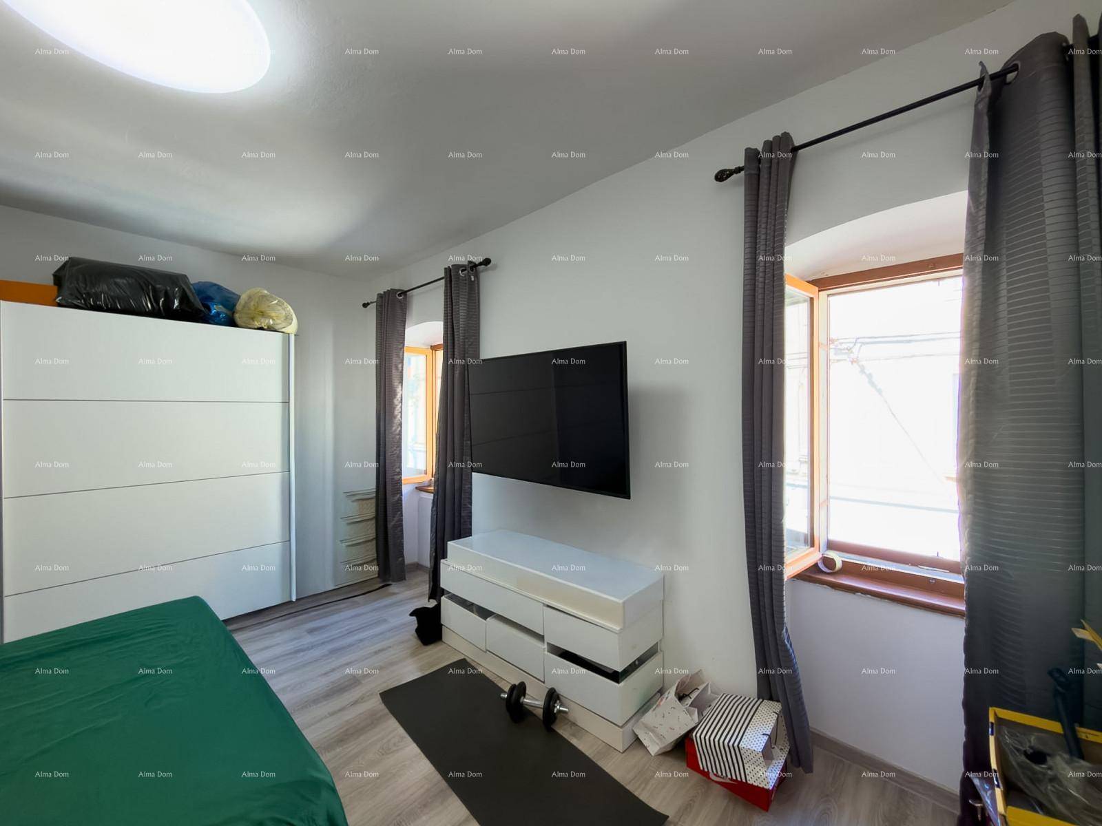 Schlafzimmer mit Doppelbett, Fernseher an der Wand und Fenster mit Vorhängen.