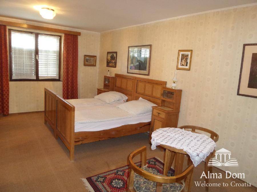 Geräumiges Schlafzimmer mit Doppelbett aus Holz, Teppichboden und gemusterter Tapete, gemütlich eingerichtet.