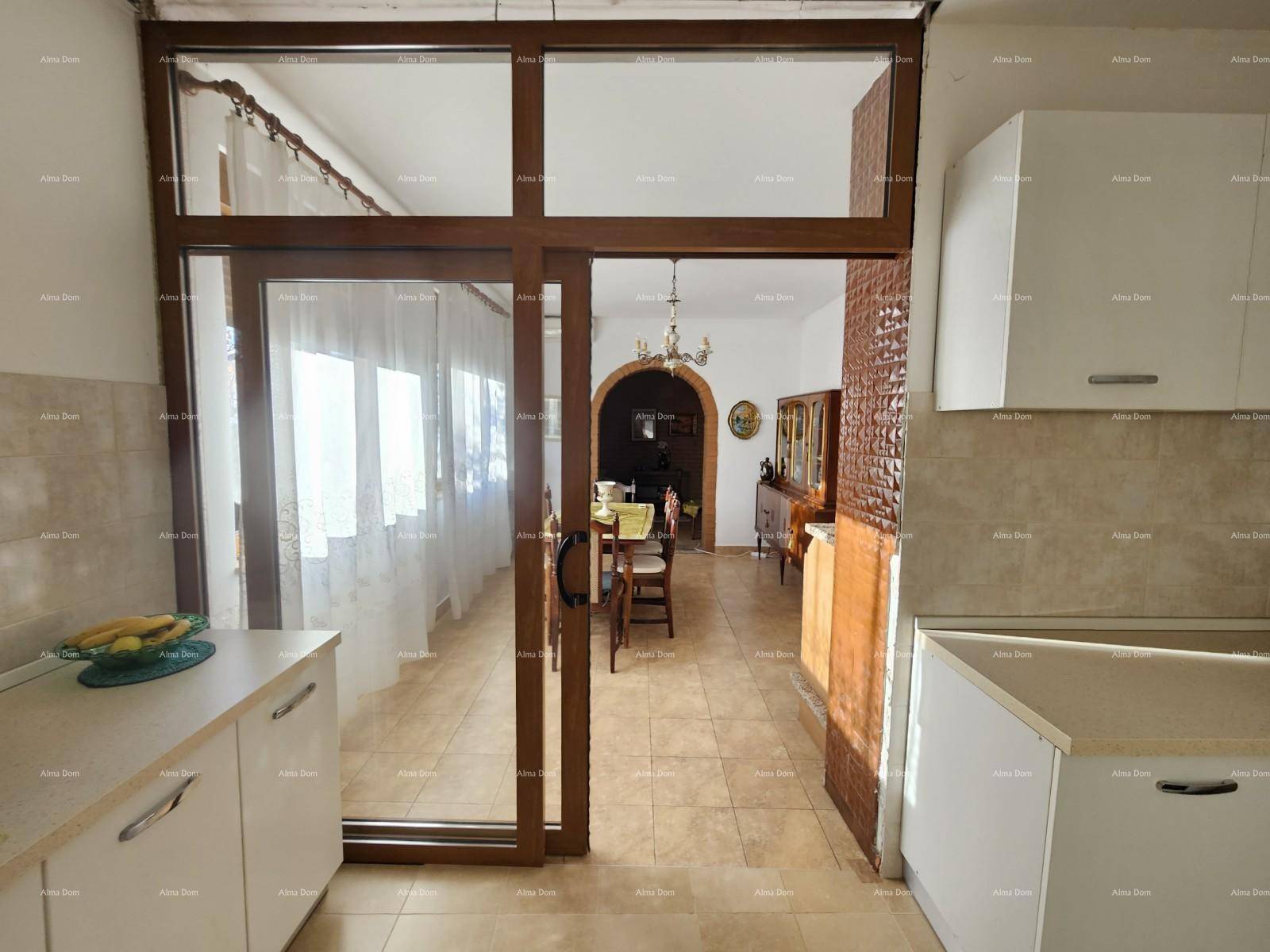 Blick von der Küche in den Essbereich durch eine große Holzschiebetür, mit Fliesenboden.