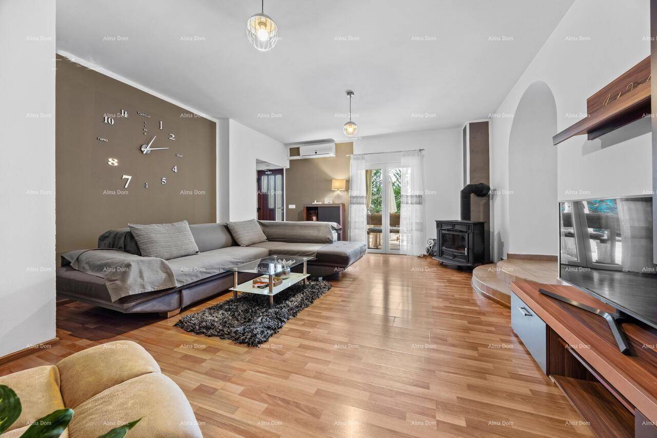 Helles Wohnzimmer mit Holzboden, Kaminofen, Klimaanlage und Zugang zu einem Außenbereich.