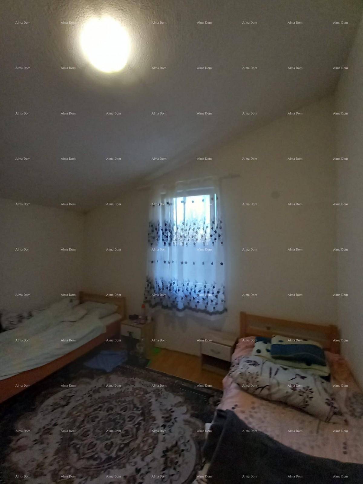 Schlafzimmer mit zwei Einzelbetten, Holzfußboden und einem Fenster mit gemusterten Vorhängen.