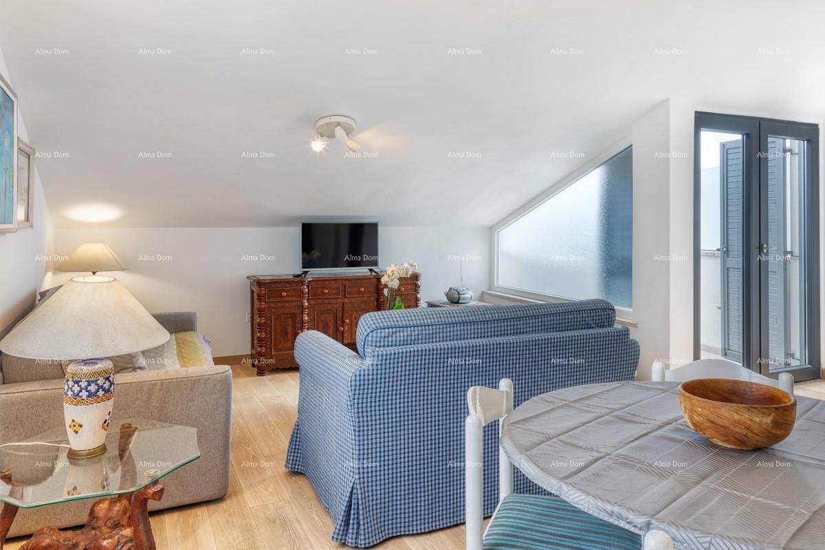 Gemütlicher Wohnbereich im Dachgeschoss mit Sofa, Holzboden und Zugang zum Balkon.