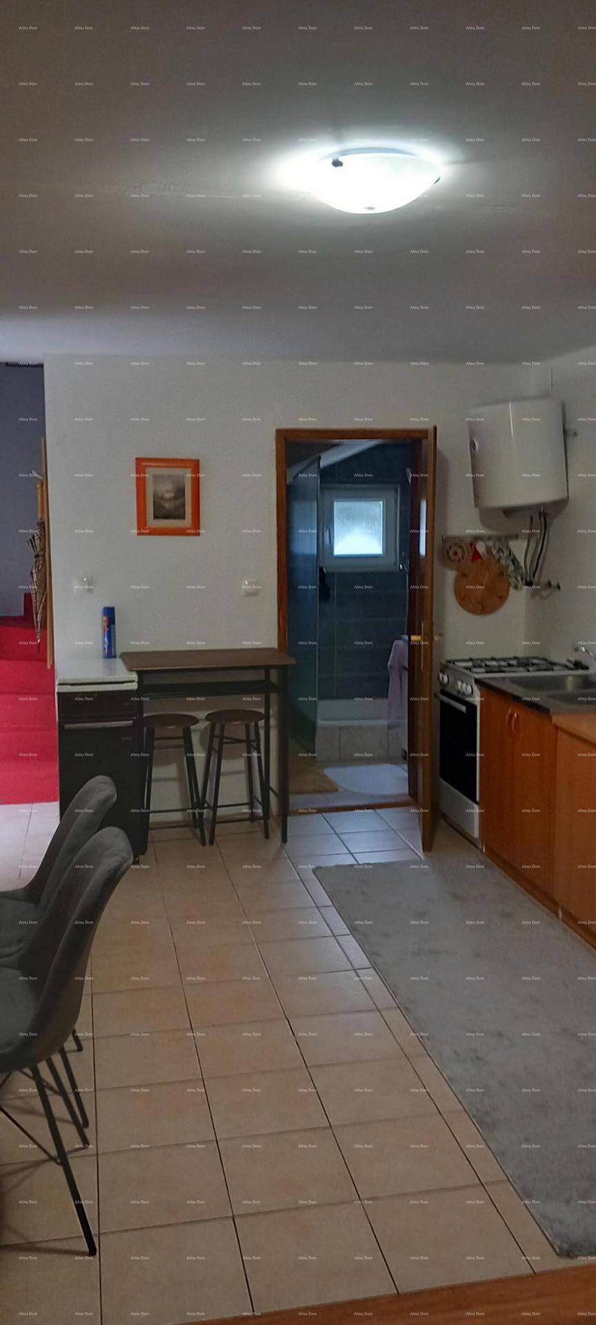 Küche mit Kochbereich, Spüle und einem kleinen Bartisch, angrenzend an ein Badezimmer.