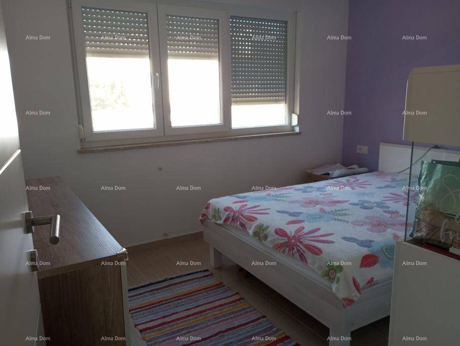 Schlafzimmer mit Bett, Holzkommode und Fenster mit Rollläden, in hellen Farben gehalten.