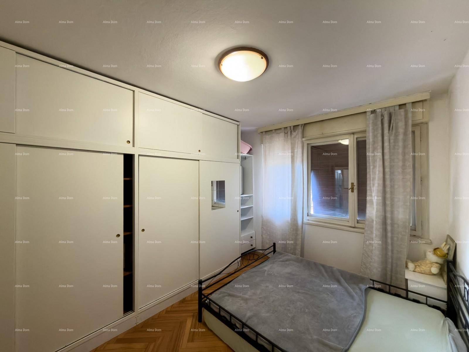 Schlafzimmer mit großem Einbauschrank, Holzfußboden und Fenster mit Vorhängen.