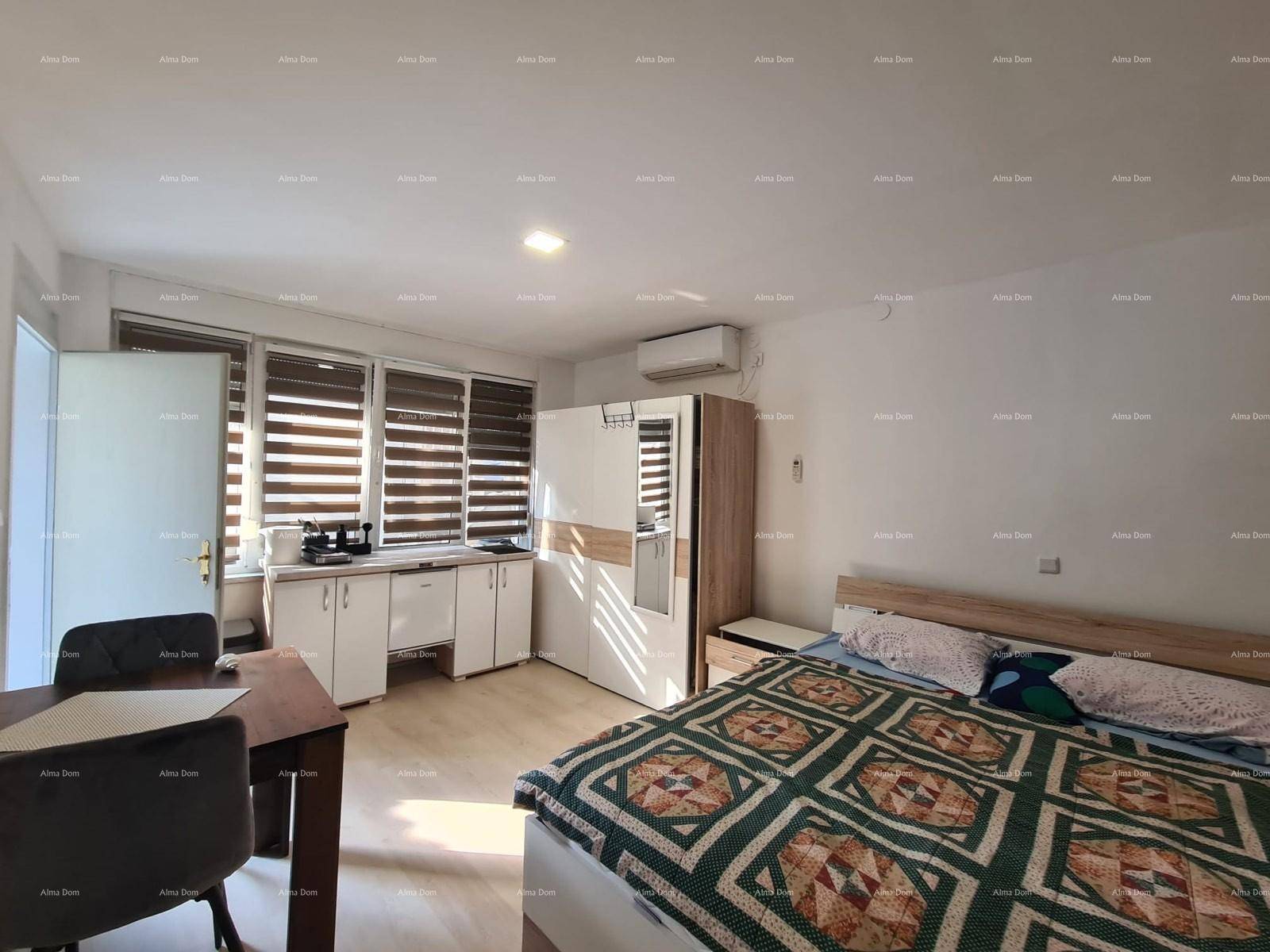 Schlafzimmer mit Doppelbett, kleiner Küchenzeile und Esstisch, mit hellem Laminatboden.