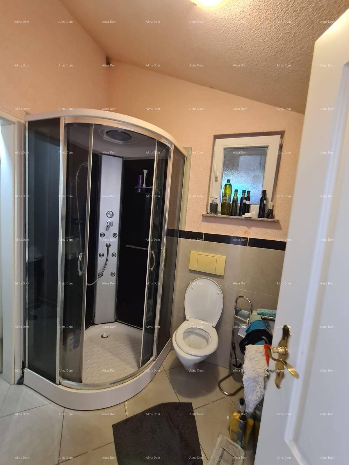 Badezimmer mit Eckduschkabine, Toilette und einem Fenster unter einer Dachschräge.