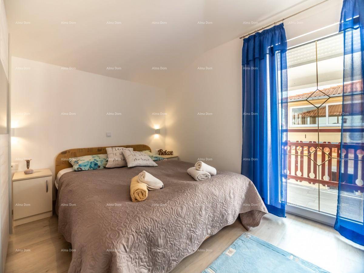 Schlafzimmer mit Doppelbett, blauen Vorhängen, Holzboden und direktem Zugang zum Balkon.