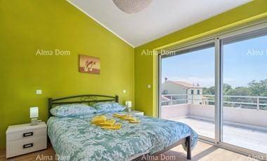 Helles Schlafzimmer mit grüner Wand, Doppelbett und großen Schiebetüren zur Terrasse.