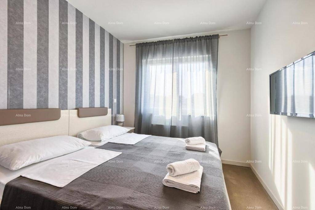 Helles Schlafzimmer mit Doppelbett, gestreifter Wand und Blick nach draußen.