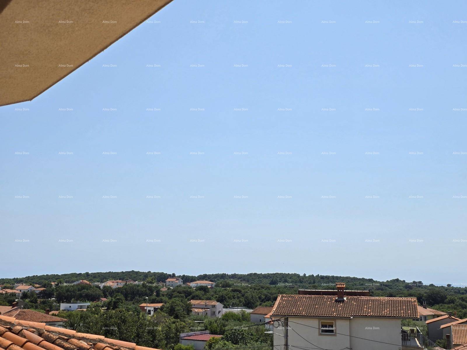 Panoramablick über die Dächer der Umgebung, grüne Landschaft und das ferne Meer unter klarem Himmel.