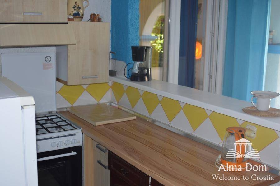 Funktionale Küche mit Holzarbeitsplatte und Durchreiche, ideal für kleine Wohnbereiche.