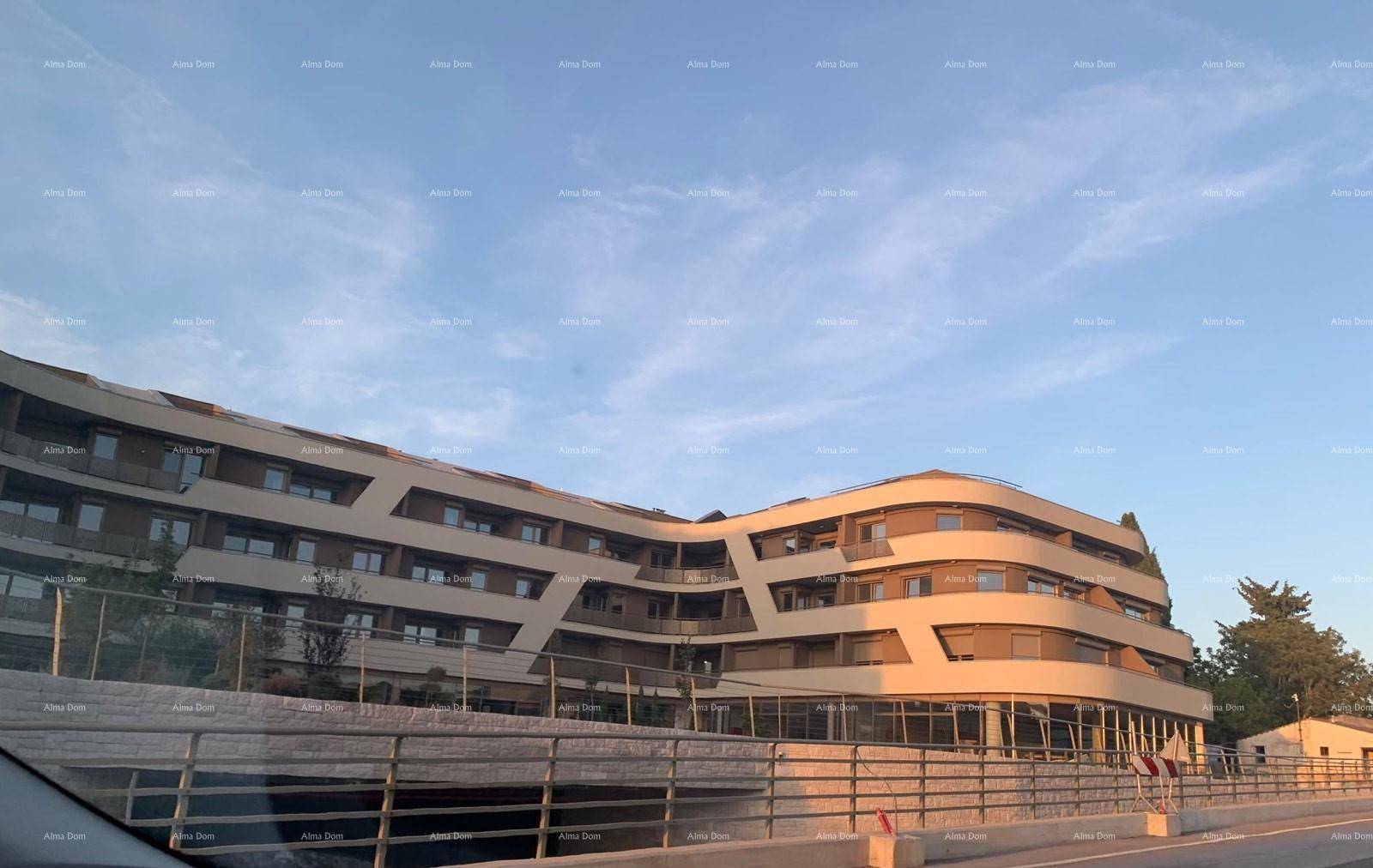 Modernes Gebäude mit geschwungener Architektur und mehreren Etagen, bei Sonnenuntergang von der Straße aus gesehen.