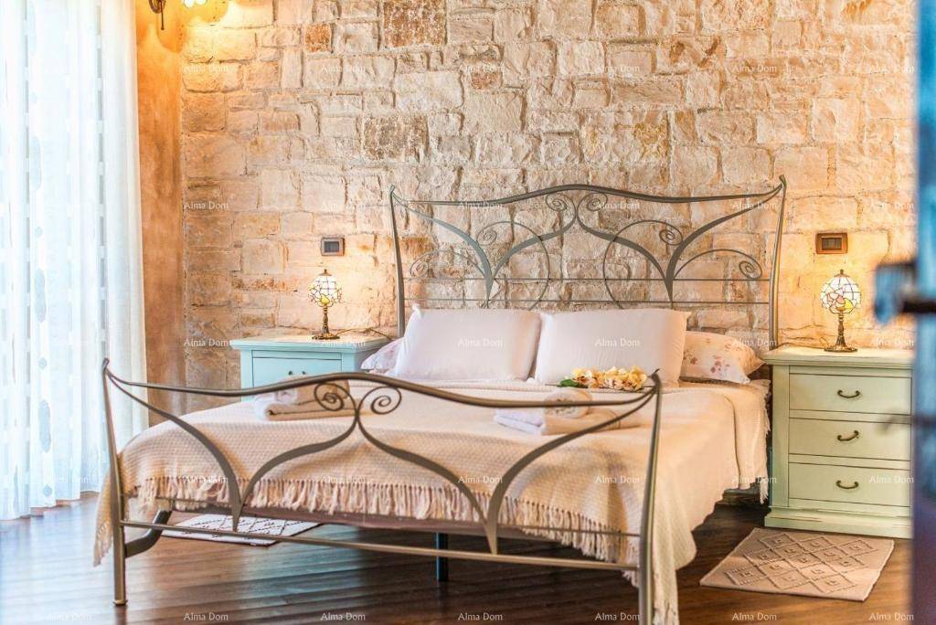 Gemütliches Schlafzimmer mit rustikaler Steinwand, Holzboden und einem schmiedeeisernen Bett.