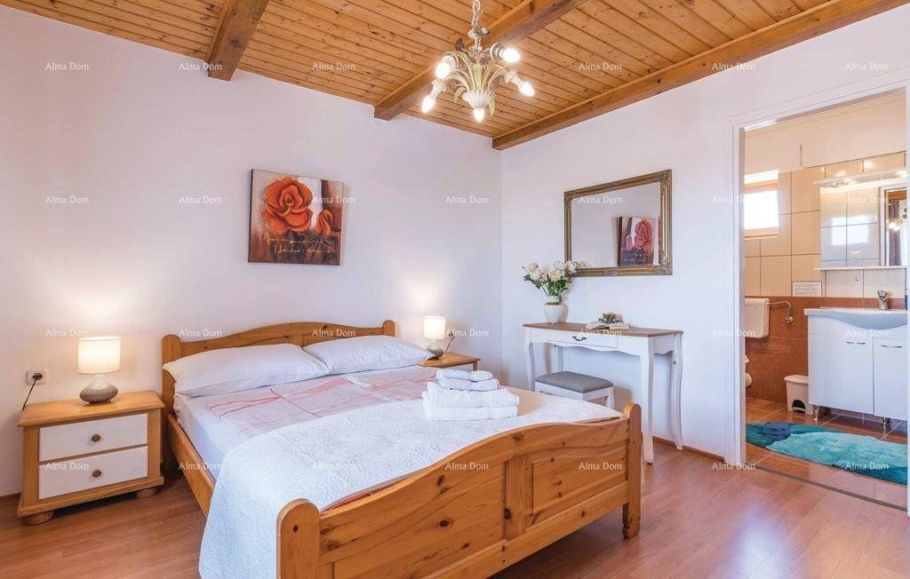 Gemütliches Schlafzimmer mit Holzbalkendecke, Doppelbett und Zugang zum Badezimmer.