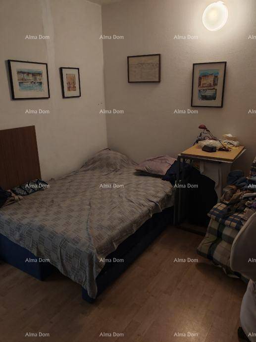 Schlafzimmer mit Einzelbett, Holzboden und gerahmten Bildern an den Wänden.