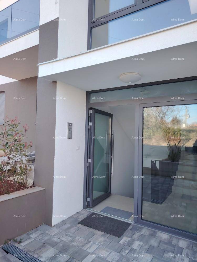 Moderner Eingangsbereich des Gebäudes mit Glastür und gepflastertem Vorplatz.
