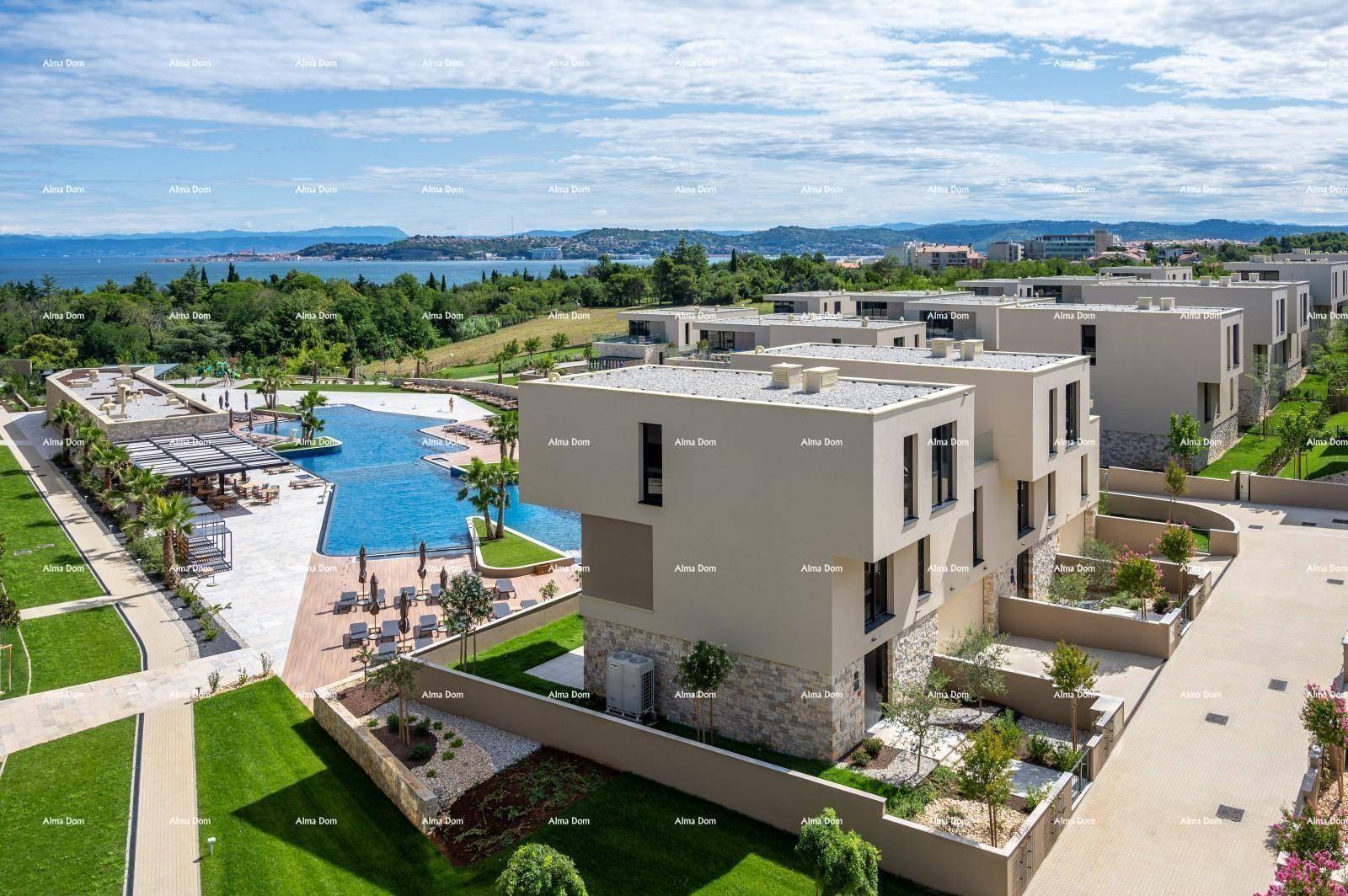 Luftaufnahme einer modernen Wohnsiedlung mit Reihenhäusern, Pool und Meerblick.