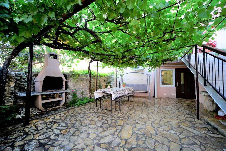 Überdachte Terrasse mit Grillplatz und Sitzgelegenheiten, umgeben von üppigem Grün.